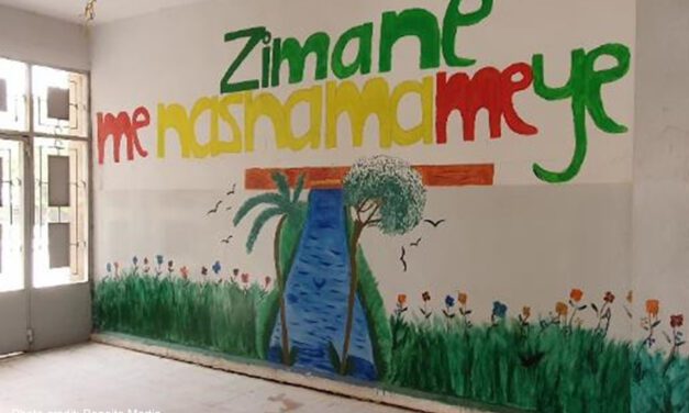 Mural on a wall in a Corridor in the school run by AANES in Qamishli. "Zimane me Nasnama me ye" with a meadow and a stream with trees.