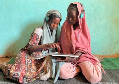 two girls with headsets and tablet devices sitting on the floor