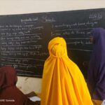 Girls look at the blackboard together in a classroom, Somalia.