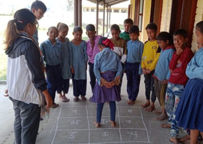 A group of girls and boys play a game on the floor where they jump on a number and then discuss an issue, Nepal.