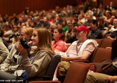 A crowd of academic conference participants sit in a lecture theatre.