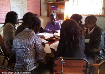 Teachers working together around a table to prepare engaging classroom activities, Zambia.