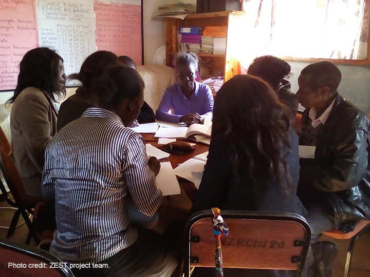 Teachers working together around a table to prepare engaging classroom activities, Zambia.