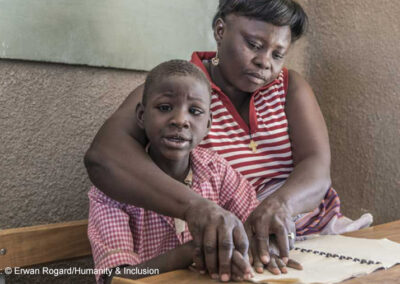 A boy receives help to read from a female teacher through an inclusive education project, Uganda.