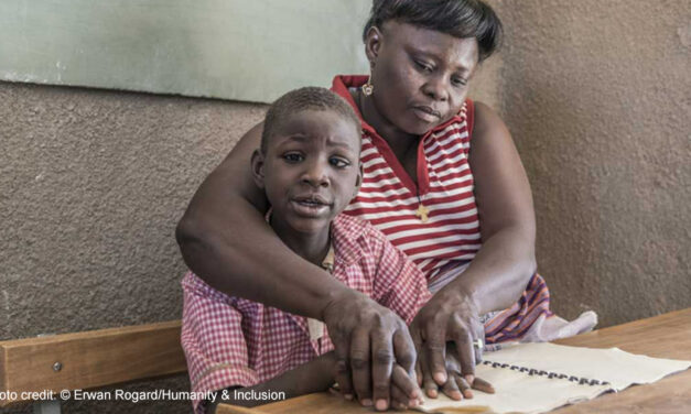 A boy receives help to read from a female teacher through an inclusive education project, Uganda.