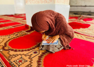 Afghan girl does her school work sitting on a carpet in a class run by Street Child Afghanistan.