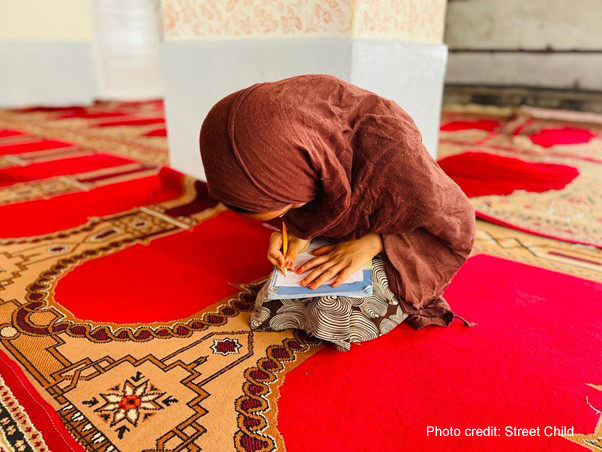 Afghan girl does her school work sitting on a carpet in a class run by Street Child Afghanistan.