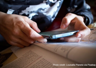 A student refers to their mobile phone alongside their textbook in class.