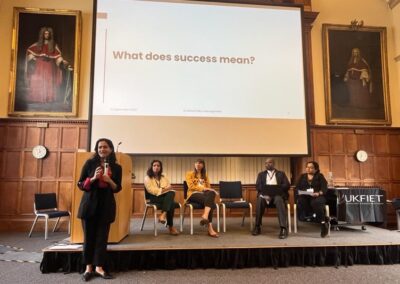 The panel presenting at the UKFIET Conference 2023 in Oxford University Examination Schools. Wooden panelling and portraits of ancient academics