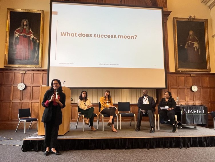 The panel presenting at the UKFIET Conference 2023 in Oxford University Examination Schools. Wooden panelling and portraits of ancient academics