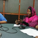 Staff from the university have a discussion in a radio broadcasting room.