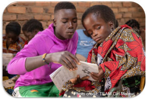 Learner with a class assistant looking at a book