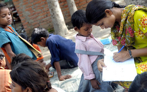 A teacher with children from an informal ‘Bus School’ project which aims to introduce children to formal nearby primary schools when the children are ready.