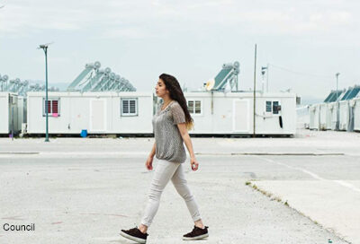 A female Syrian refugee walking across refugee camp in Jordan.
