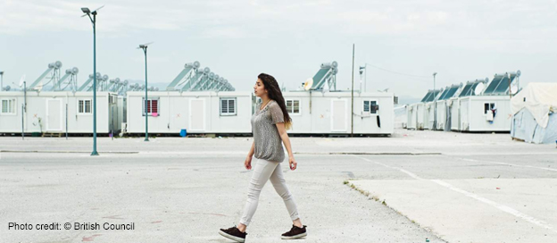 A female Syrian refugee walking across refugee camp in Jordan.