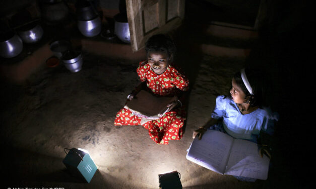 Two girls study by solar light at night in Tinginaput, rural Orissa, India