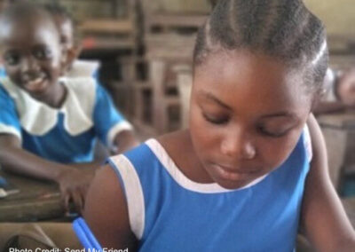 Girl dressed in blue writes in classroom.