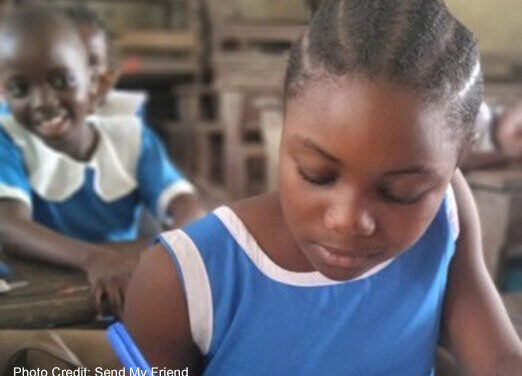 Girl dressed in blue writes in classroom.