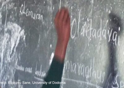 An arm reaches up to write on the blackboard.