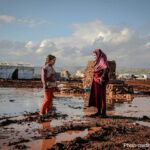 Woman in Hijab Talking with Girl, Idlib, Syria. Area is muddy and flooded