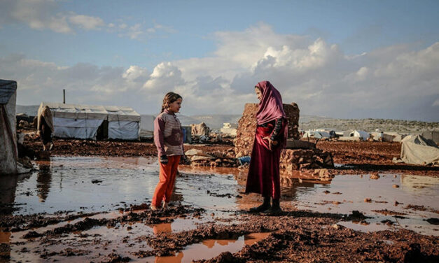 Woman in Hijab Talking with Girl, Idlib, Syria. Area is muddy and flooded