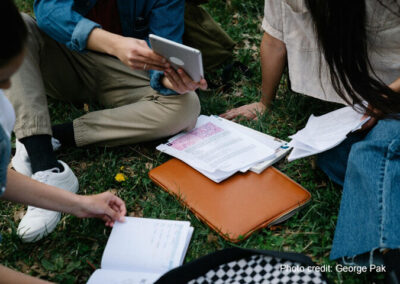 Group of university students study together sitting on the ground.