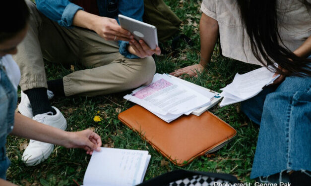 Group of university students study together sitting on the ground.