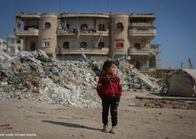 Girl stands in front of ruined buildings