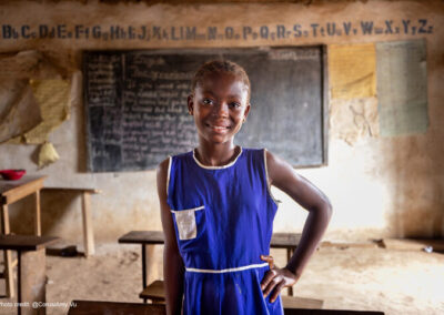 Kadiatu, 12, wearing a blue unform, received monthly cash transfers and follow up support to help her stay in school as part of the Girls In School Initiative, Sierra Leone.