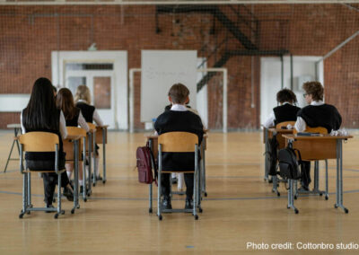 boys and girls sit with their backs to the camera in an exam hall at separated desk.