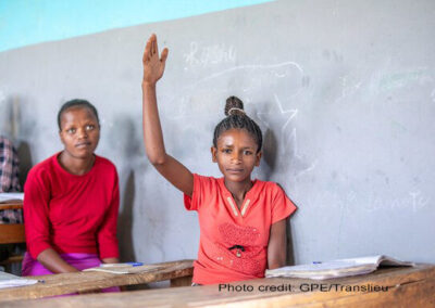 A female student wearing red, lifts her hand in class, Yirba Yanase Primary and Secondary School, Hawassa, Ethiopia.