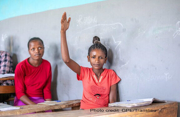 A female student wearing red, lifts her hand in class, Yirba Yanase Primary and Secondary School, Hawassa, Ethiopia.