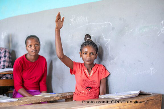A female student wearing red, lifts her hand in class, Yirba Yanase Primary and Secondary School, Hawassa, Ethiopia.