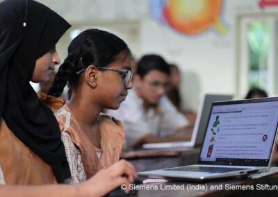 Technology-driven STEM learning in action. Three students sit around a laptop in a classroom.
