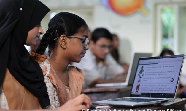 Technology-driven STEM learning in action. Three students sit around a laptop in a classroom.