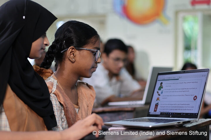 Technology-driven STEM learning in action. Three students sit around a laptop in a classroom.