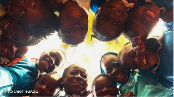 Enhancing educational outcomes Children stand in a circle and look down to the camera in the middle of the floor.