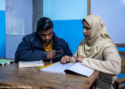 Female teacher sits with a male student at a non-formal education centre in Lahore, Pakistan.
