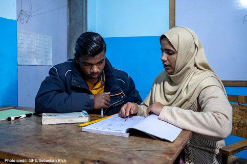 Female teacher sits with a male student at a non-formal education centre in Lahore, Pakistan.