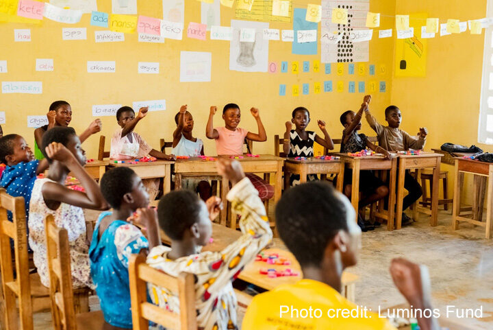 Children sit in class and put their hands up, Ghana