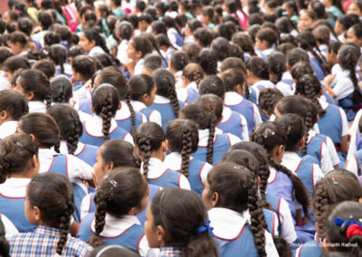 Schoolgirls in uniforms sit with their back to the camera, India.