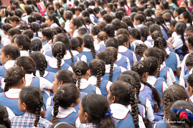 How colonialism Schoolgirls in uniforms sit with their back to the camera, India.