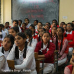 Girls sit in a packed classroom, India.