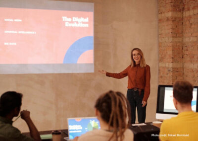 Teacher stands in front of a presentation on the digital screen.