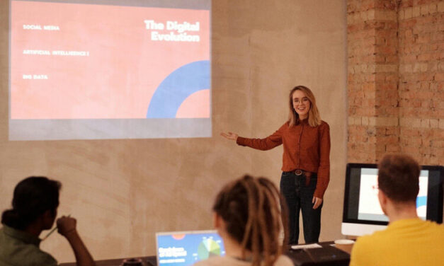 Teacher stands in front of a presentation on the digital screen.