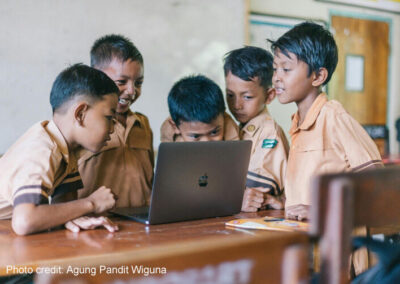 Boys crowd around a laptop, Indonesia.