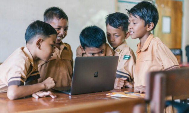 Boys crowd around a laptop, Indonesia.