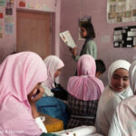 Girls discuss work together in the classroom.