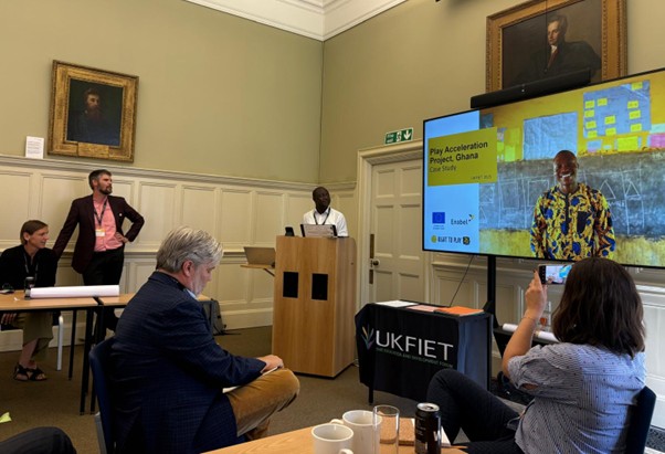 Photo of session at the UKFIET conference with a presenter and slides for a case study in Ghana