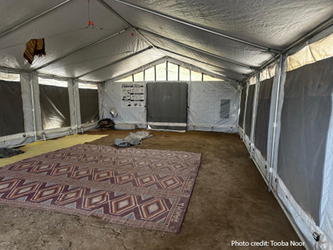 A temporary learning space in Sindh province, Pakistan. A patterned rug on the floor of a tented building